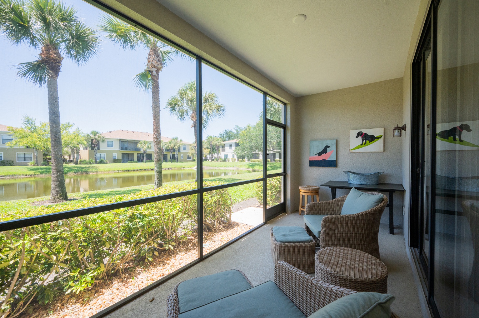Screened lanai with seating area overlooking the pond and palm trees