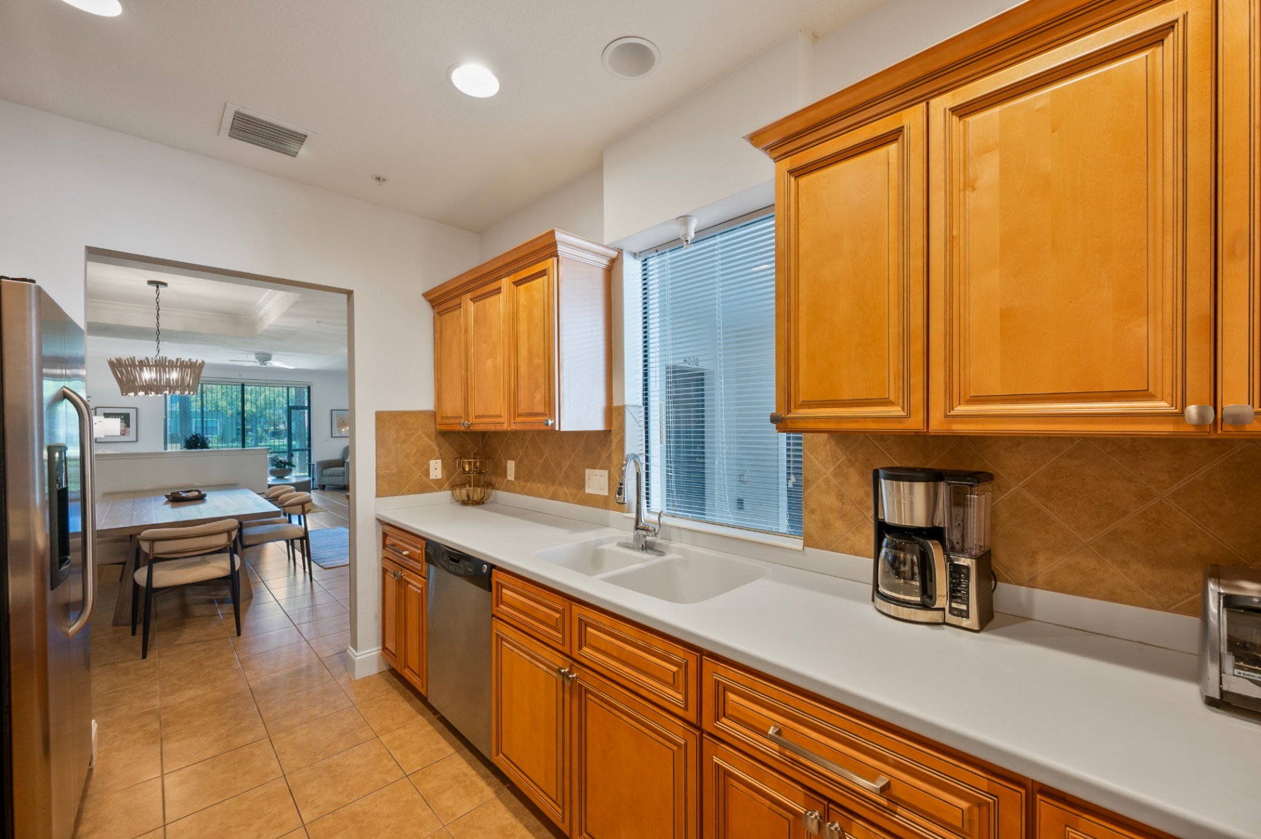 Kitchen sink wall with tall cabinetry and dining room beyond