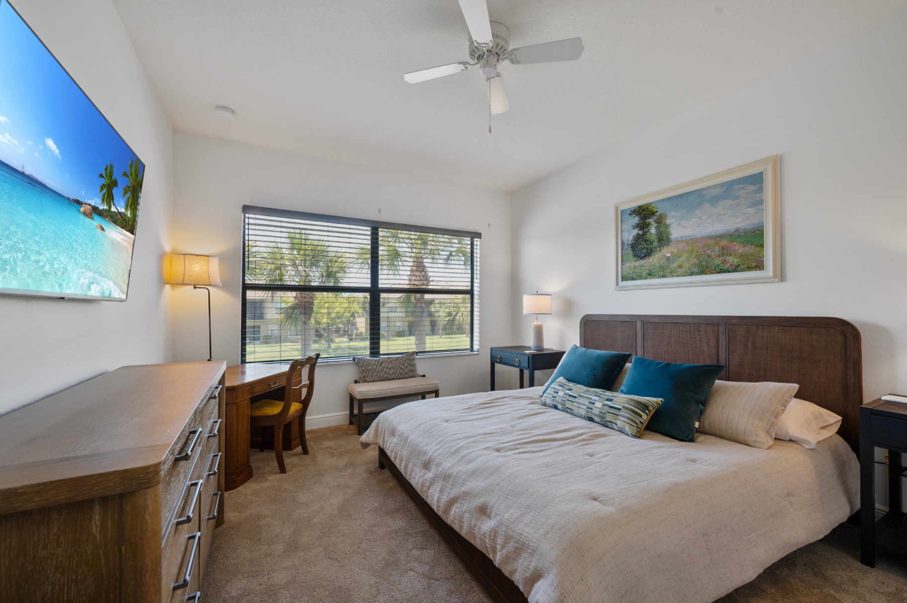 Furnished bedroom with television, dresser, and window-side desk