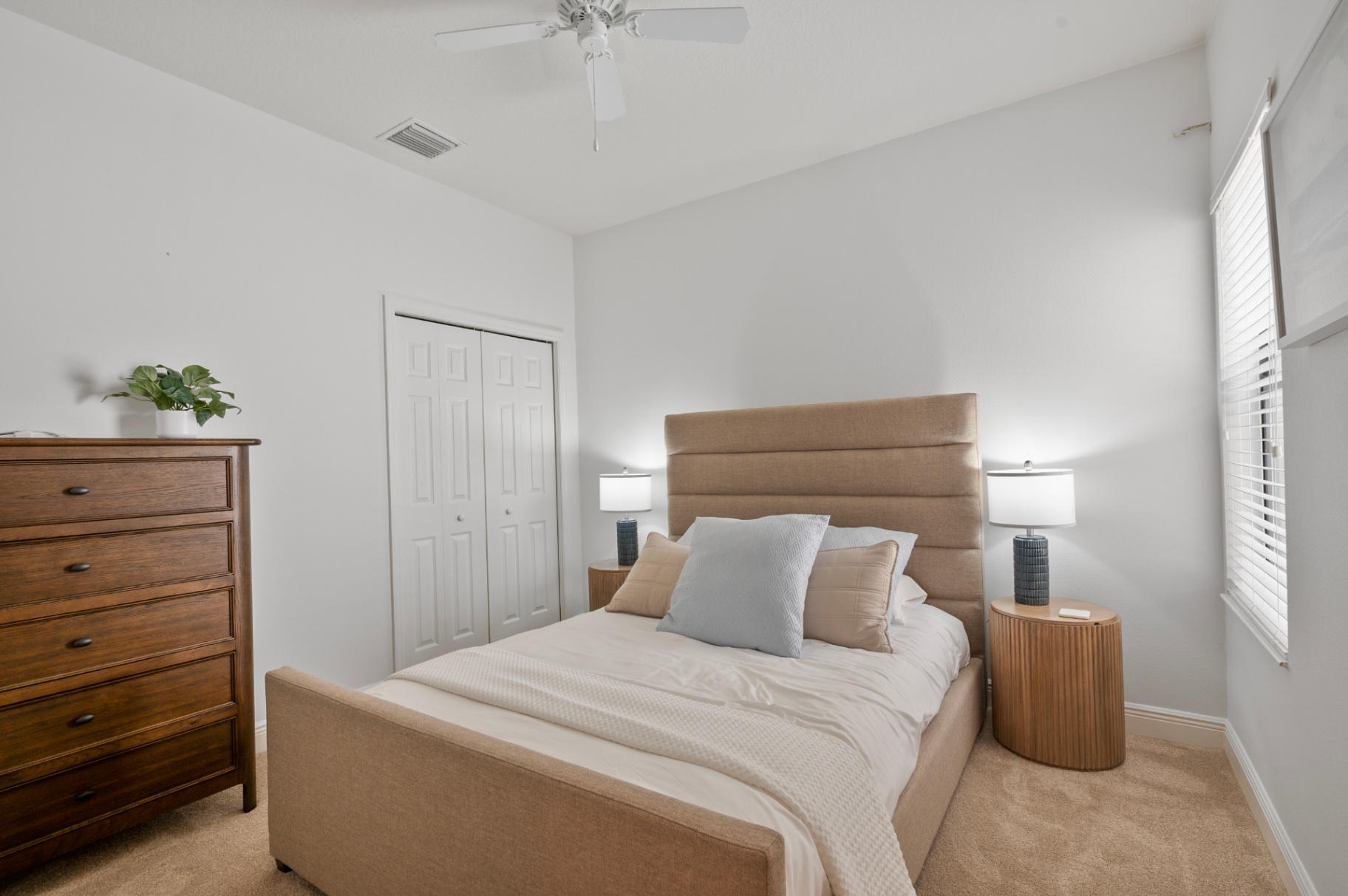 Guest bedroom with upholstered bed, side tables, and dresser